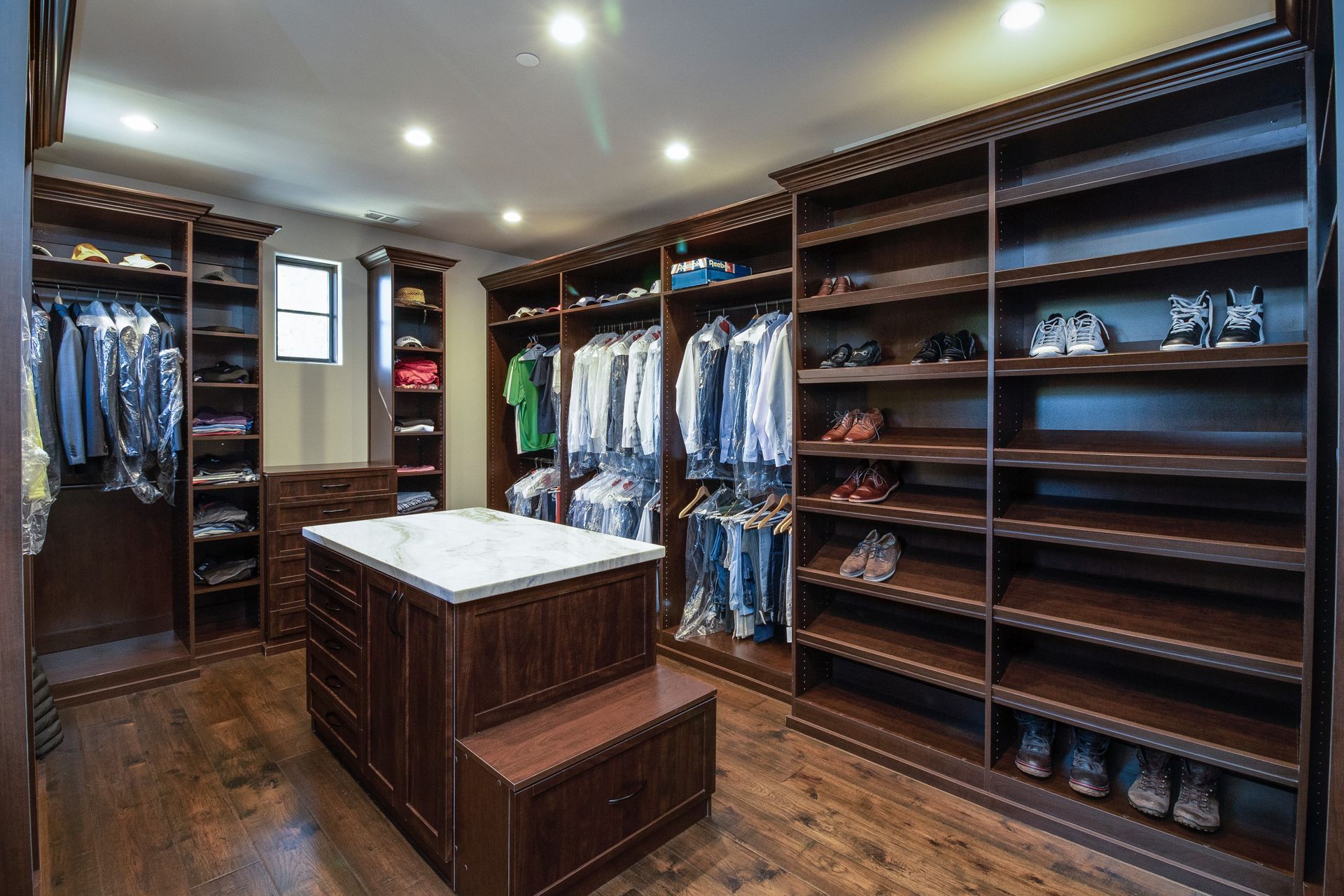 A walk in closet filled with lots of clothes and shoes.