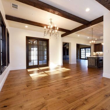A large empty room with hardwood floors and a chandelier.