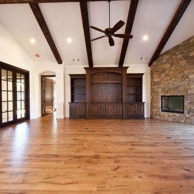 An empty living room with hardwood floors and a ceiling fan
