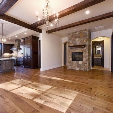 A living room with hardwood floors and a stone fireplace.