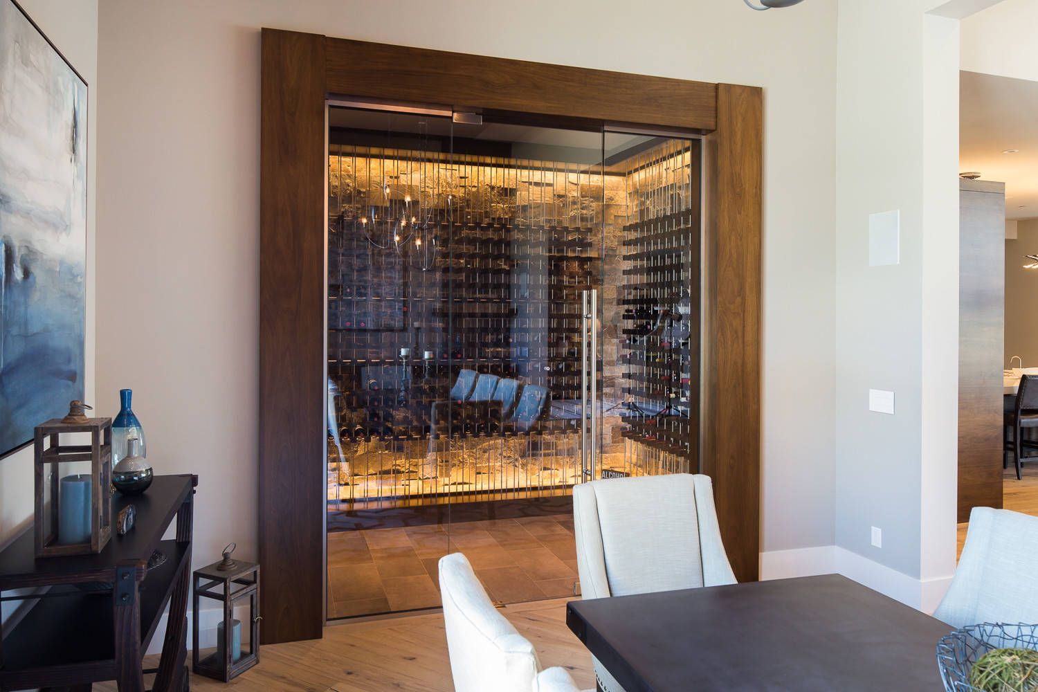 A dining room with a table and chairs next to a wine cellar.