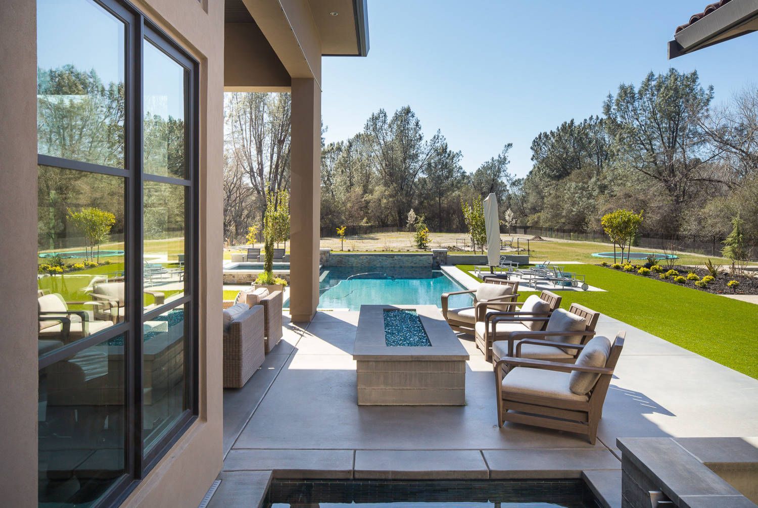 A patio with a fire pit and a pool in the backyard of a house.