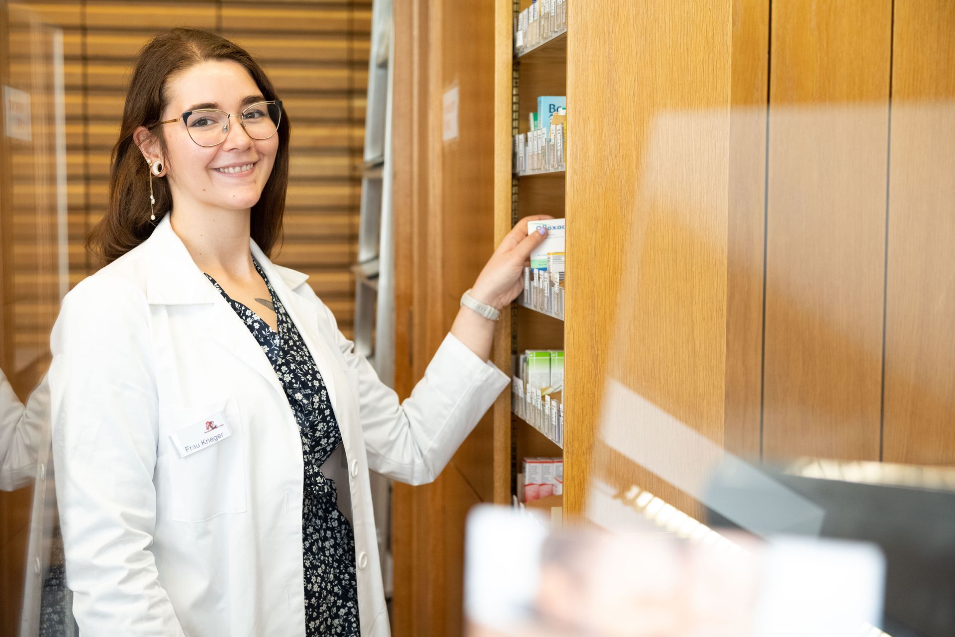 Eine Apothekerin steht vor einem Regal in einer Apotheke.