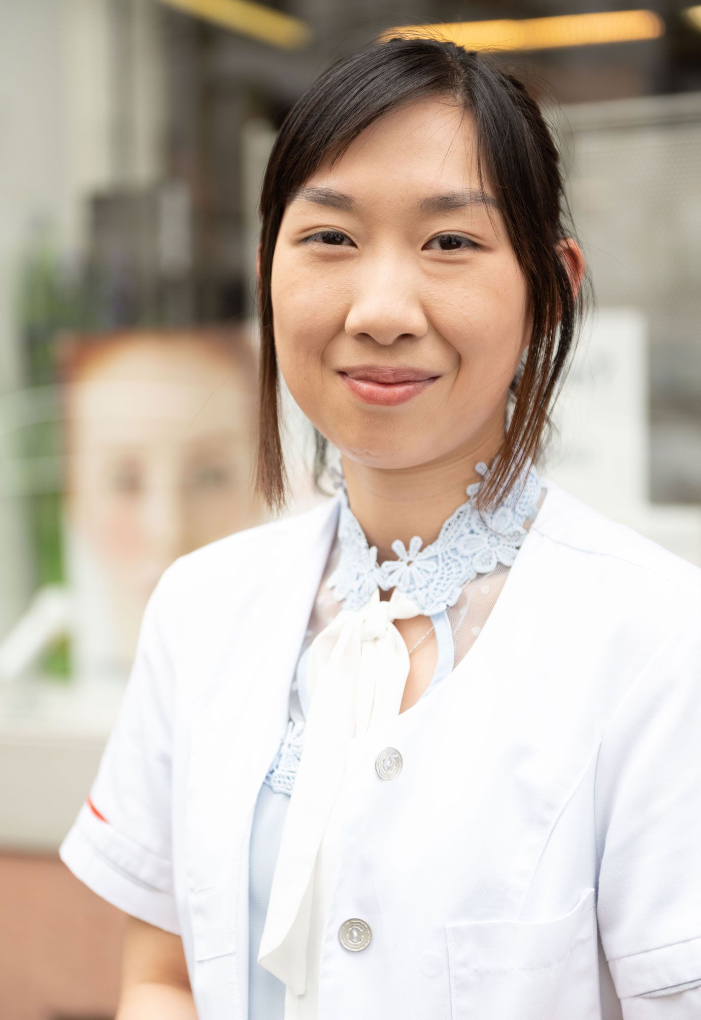 Eine Frau in einem weißen Laborkittel lächelt in die Kamera.