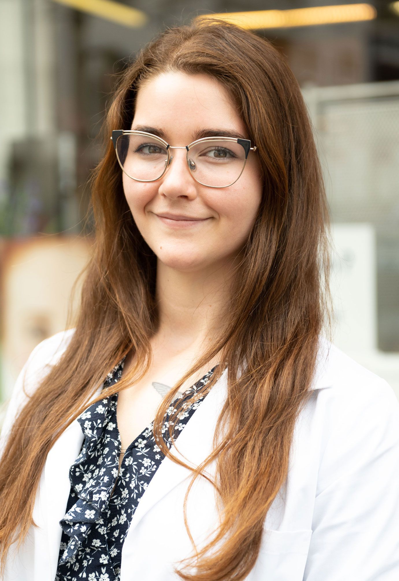 Eine Frau mit Brille und weißem Kittel lächelt in die Kamera.