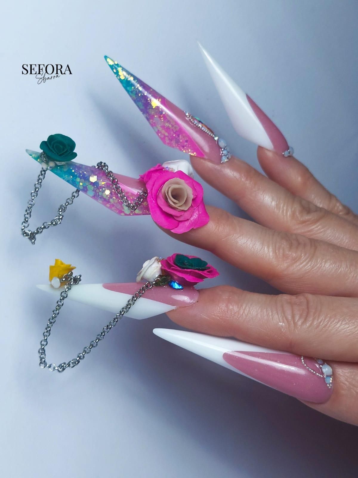 Le unghie di una donna sono decorate con fiori e catene