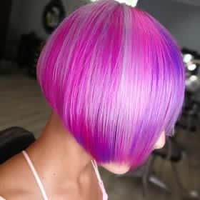 Una donna con i capelli rosa e viola è seduta su una sedia.