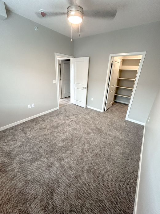 An empty bedroom with a ceiling fan and a walk in closet.