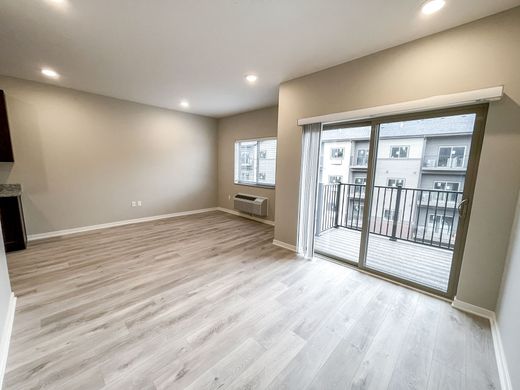 An empty living room with a balcony and sliding glass doors.