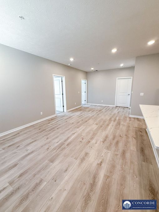 An empty living room with hardwood floors and gray walls.