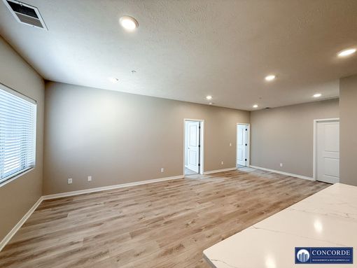 An empty living room with hardwood floors and a window