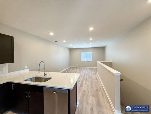 A kitchen with a sink , dishwasher , and cabinets.