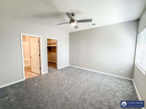 An empty bedroom with a ceiling fan and a walk in closet.