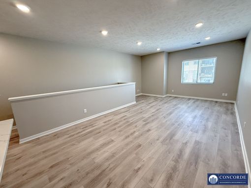 An empty living room with hardwood floors and a window.
