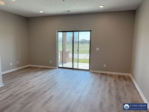 An empty living room with hardwood floors and a sliding glass door.
