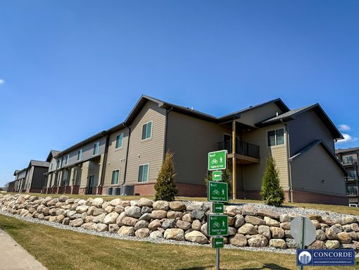 A large apartment building with a stone wall in front of it