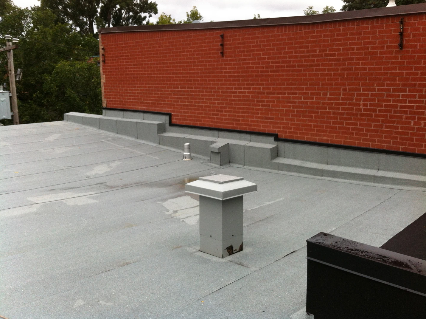 Un toit avec une cheminée dessus et un mur de briques derrière