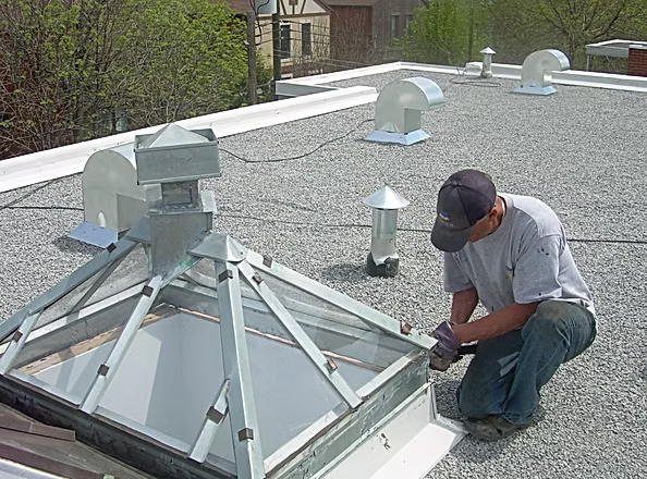 Un homme travaille sur une lucarne sur le toit d'un immeuble