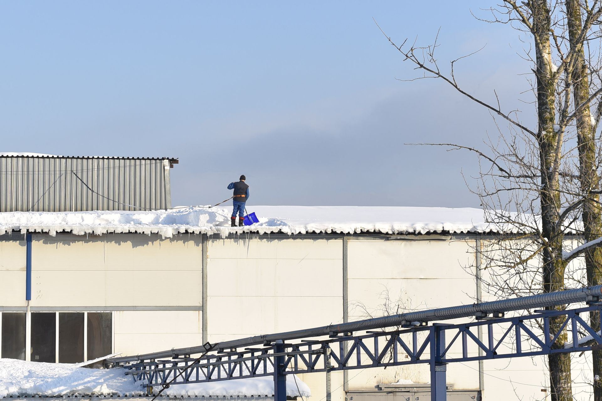 Un homme enlève la neige du toit d'un bâtiment.