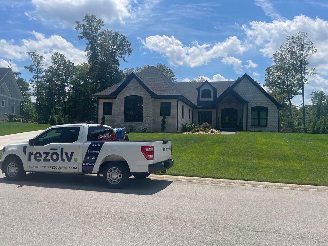 A white truck is parked in front of a large house.