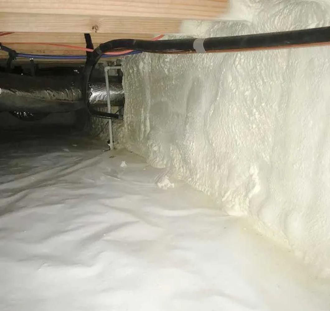 A crawl space filled with a lot of foam and pipes.