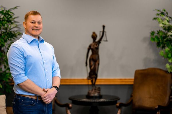 Caden Butler posing in front of a small bronze statue of Lady Justice