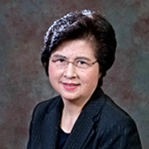 A woman in a suit and glasses is smiling for the camera.