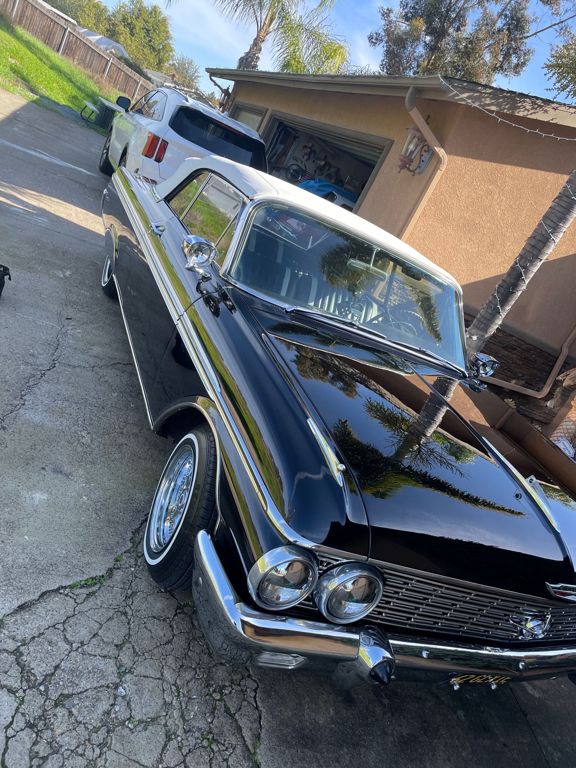 A black and white car is parked in front of a house.
