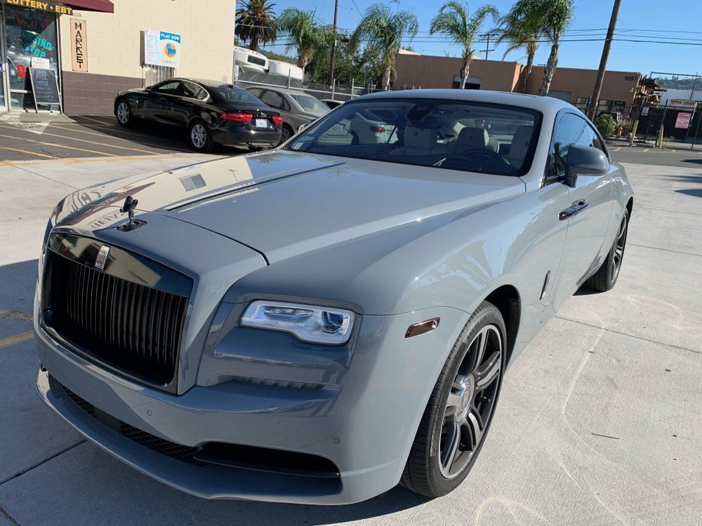 A gray rolls royce wraith is parked in a parking lot.