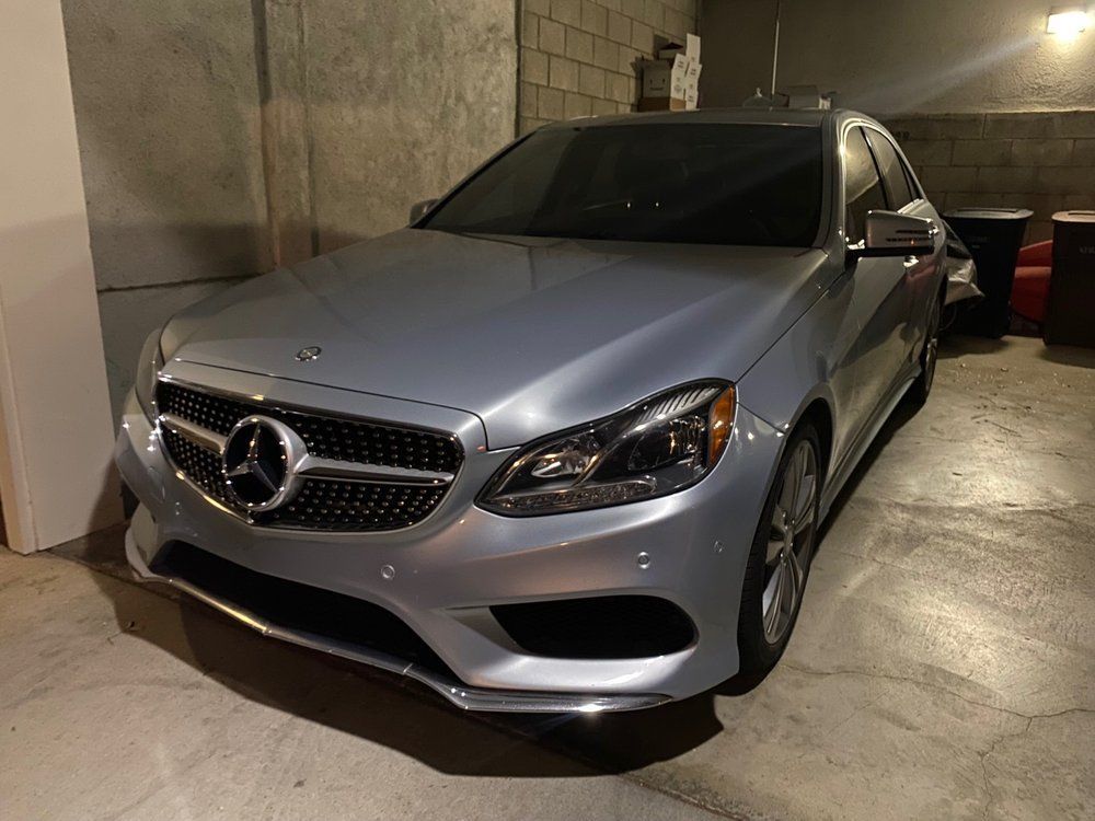 A silver mercedes benz is parked in a garage.