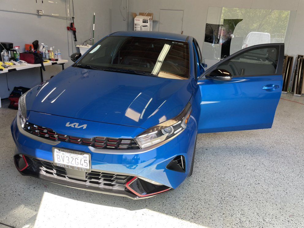 A blue car is parked in a garage with its doors open.
