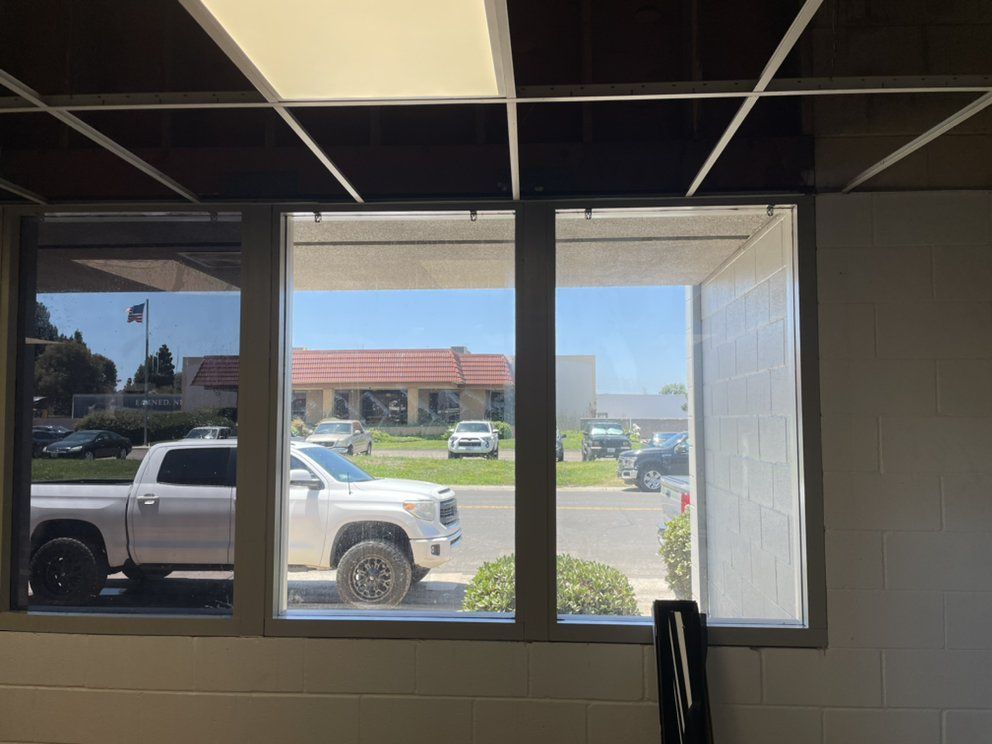 A white truck is parked in front of a window in a building.