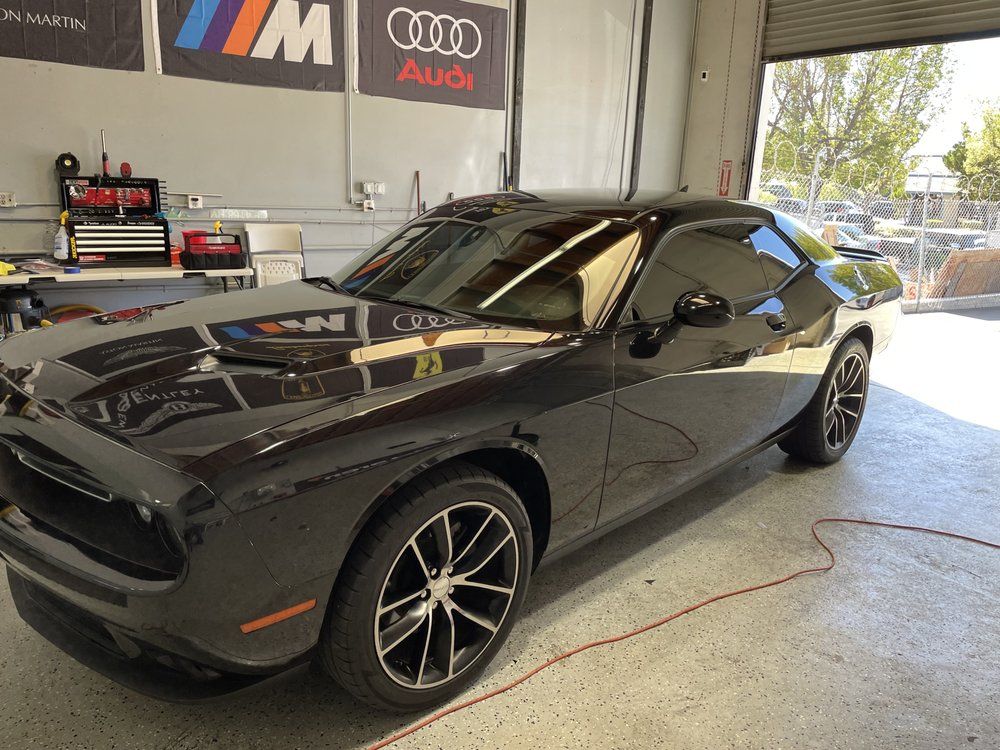 A black dodge challenger is parked in a garage.