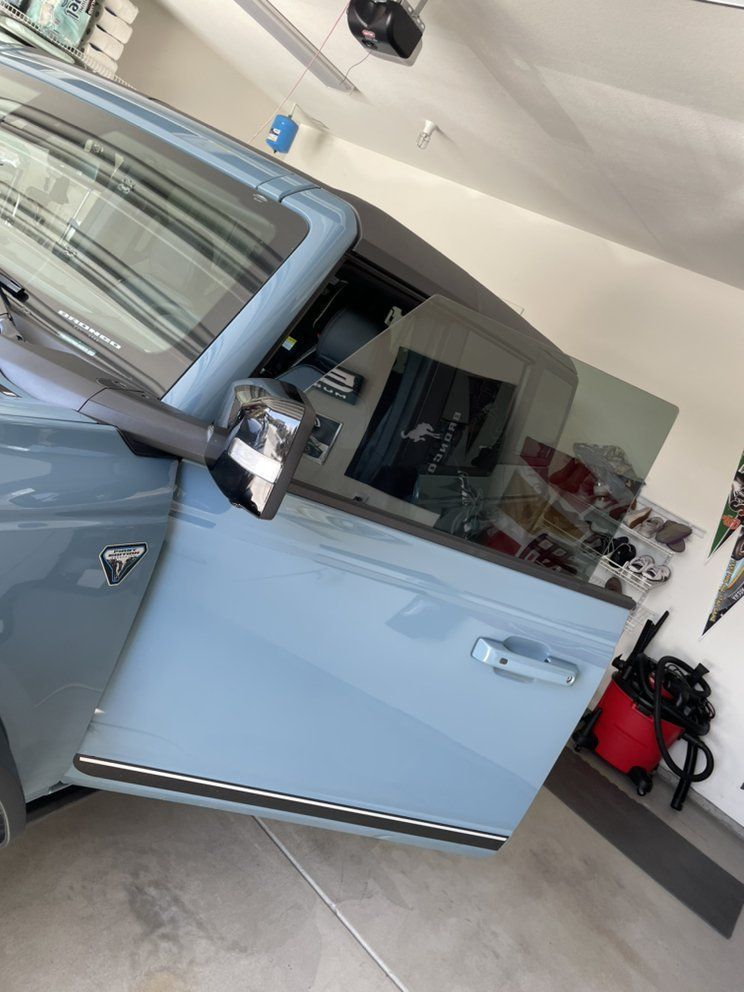 A blue car is parked in a garage with its door open.
