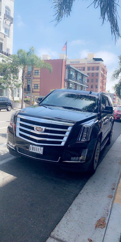 A black cadillac escalade is parked on the side of the road.