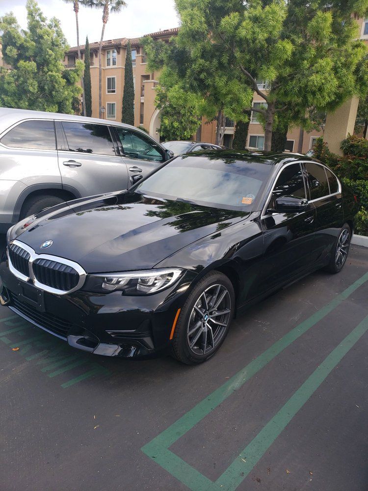 A black bmw 3 series is parked in a parking lot.