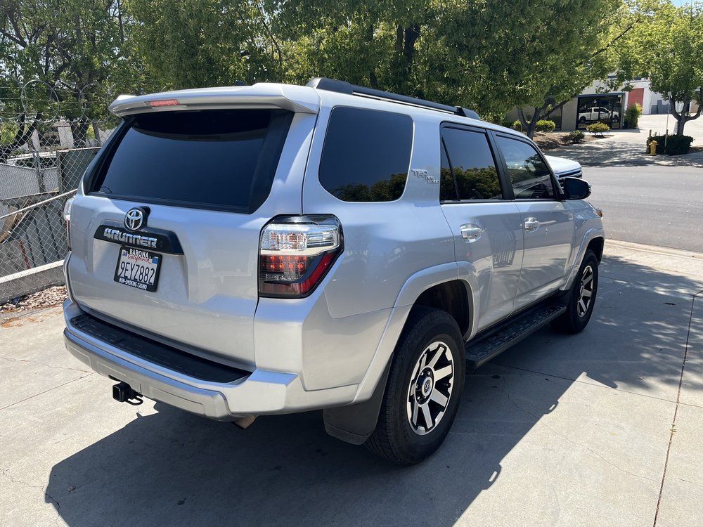 A silver toyota 4runner is parked on the side of the road.