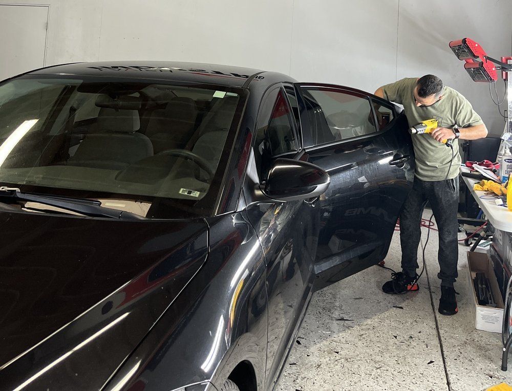 A man is working on a black car in a garage.