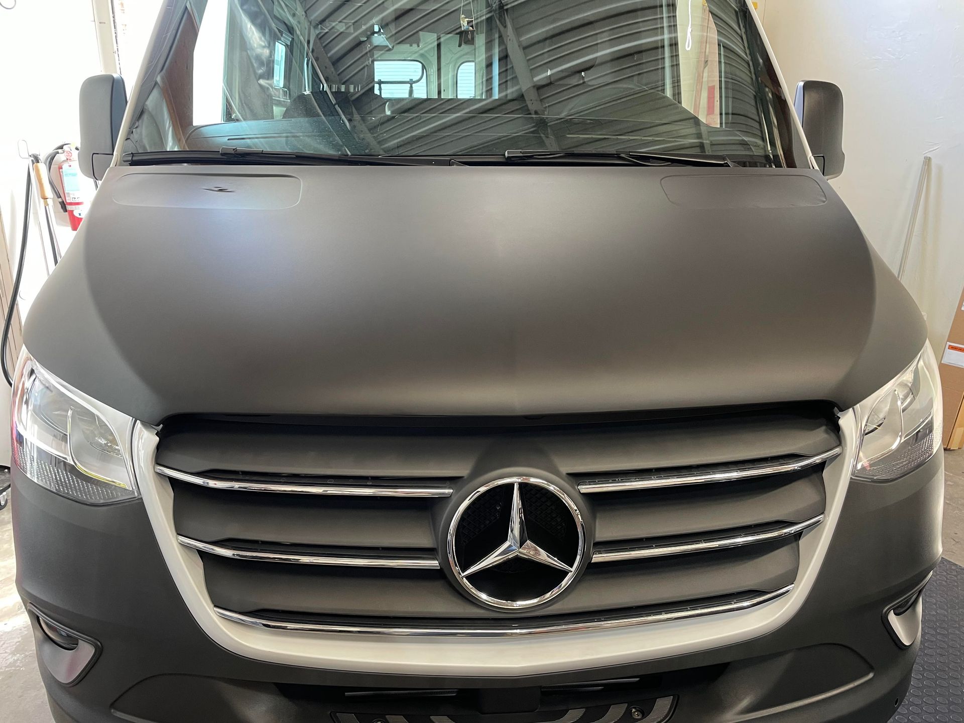 A black mercedes van is parked in a garage.