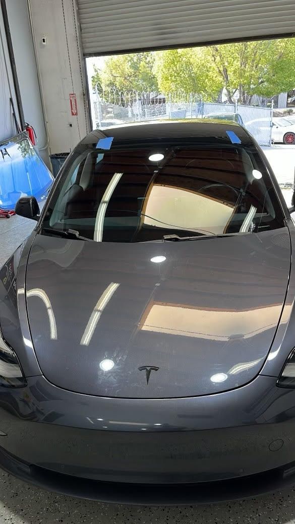 A gray tesla model 3 is parked in a garage.