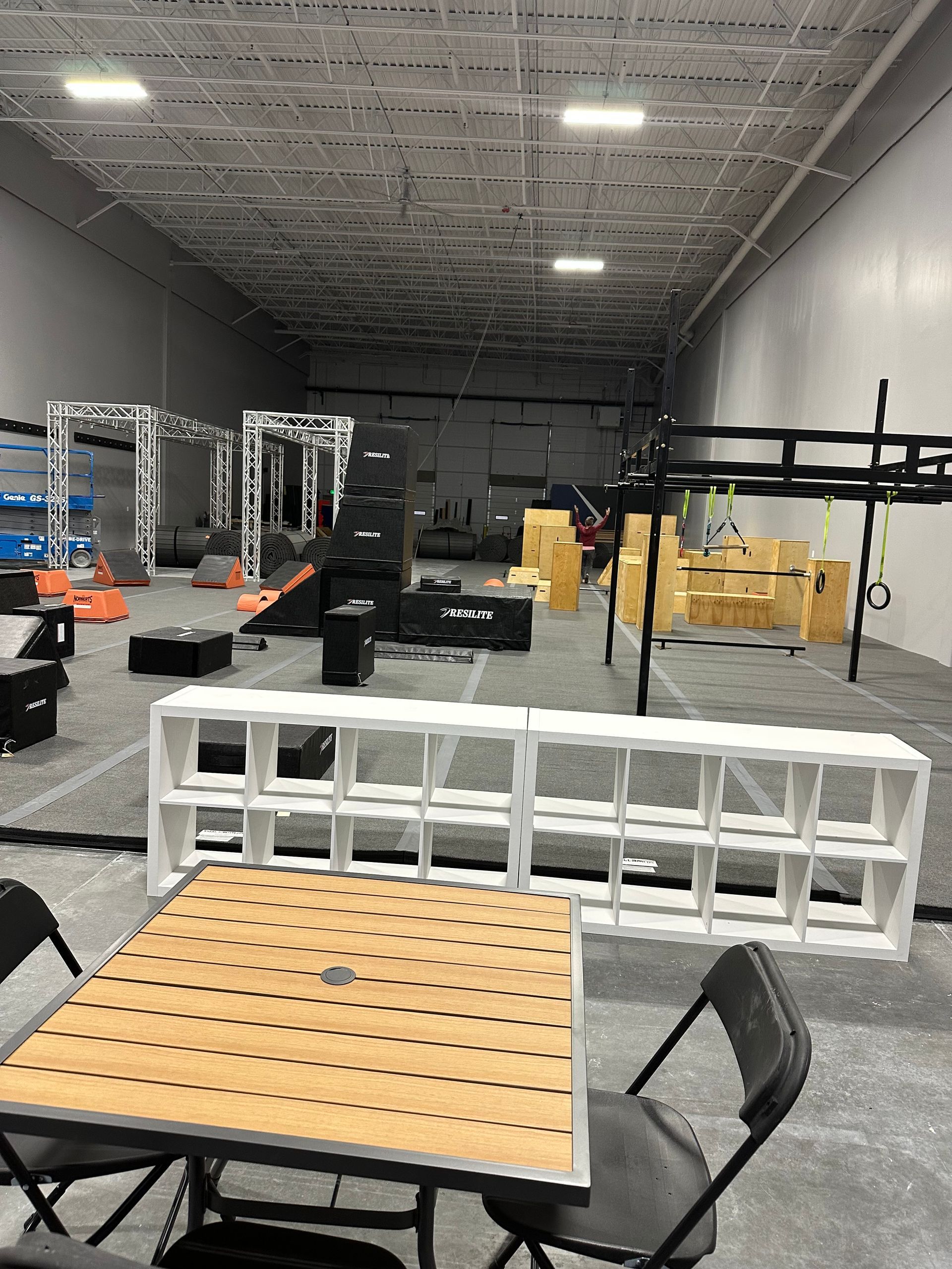 Indoor obstacle course with various structures: climbing walls, bars, and a table with chairs.