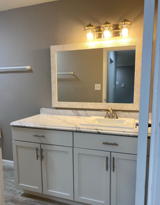 A bathroom with white cabinets and a large mirror