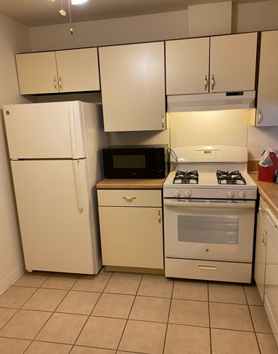A kitchen with a stove a refrigerator and a microwave