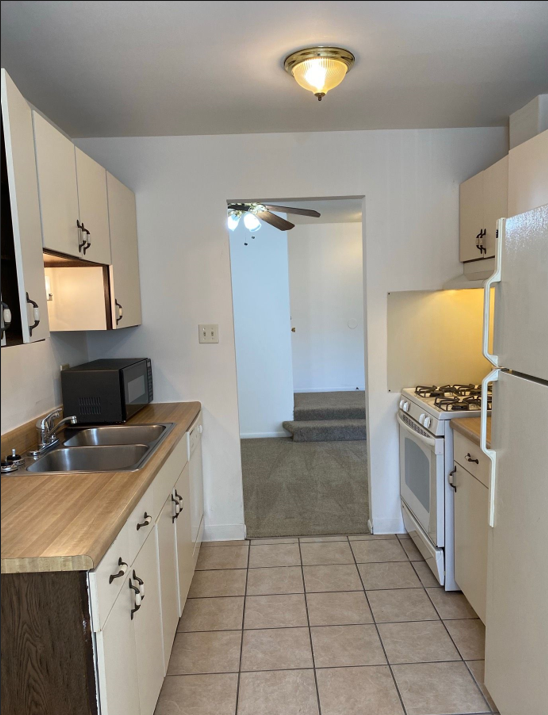 A kitchen with white cabinets and a white refrigerator