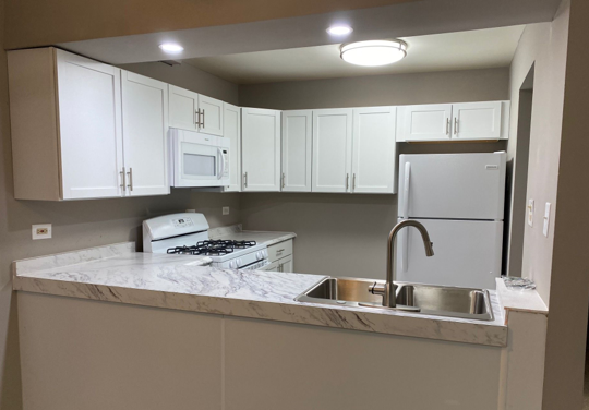 A kitchen with white cabinets and a stainless steel sink