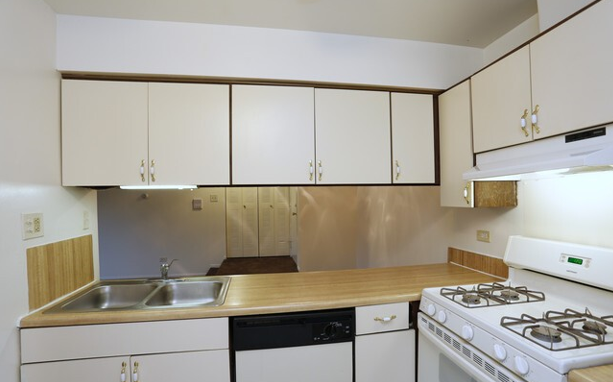 A kitchen with white cabinets and a stove top oven