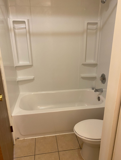 A bathroom with a tub , toilet and shower.