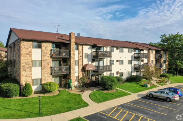 A large apartment building with cars parked in front of it.