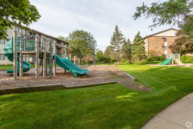 A playground with a slide and a swing set in front of a building.