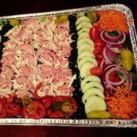Tray of assorted cold-cut ingredients: meats, veggies, cheeses, olives, and tomatoes.